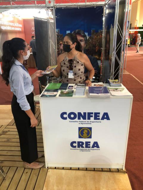 Funcionária da Gerência de Comunicação do Confea, Alessandra Porto recebe profissional no estande conjunto do Confea e do Crea em Francisco Beltrão